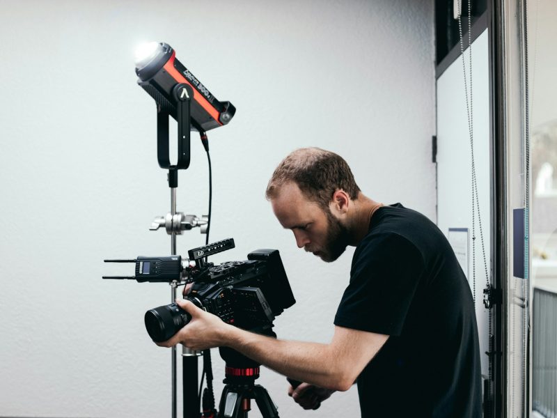 man in black crew neck t-shirt holding black and red camera